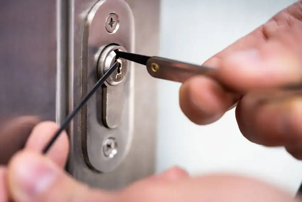 Close-up of hands using lock picking tools to open a metal door lock, demonstrating expert locksmith services NYC.